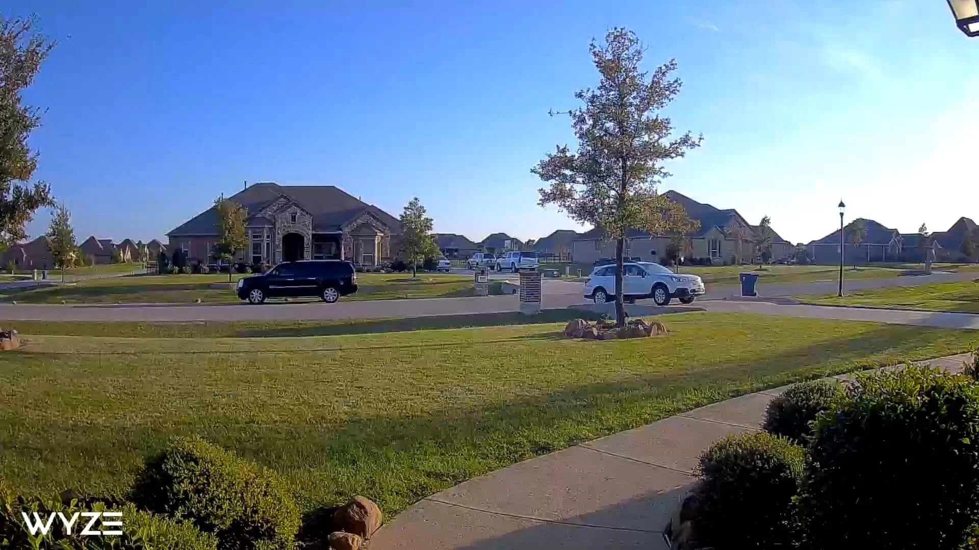 Wide angle view of the front of a house with cars off in the distance.