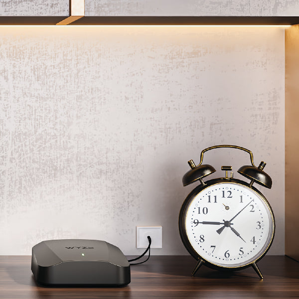 Mesh Router Pro sitting on a bookshelf beside a clock.