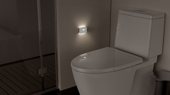 nite light mounted on wall next to a toilet 