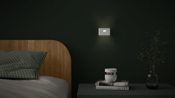 nite light mounted on wall next to a bed