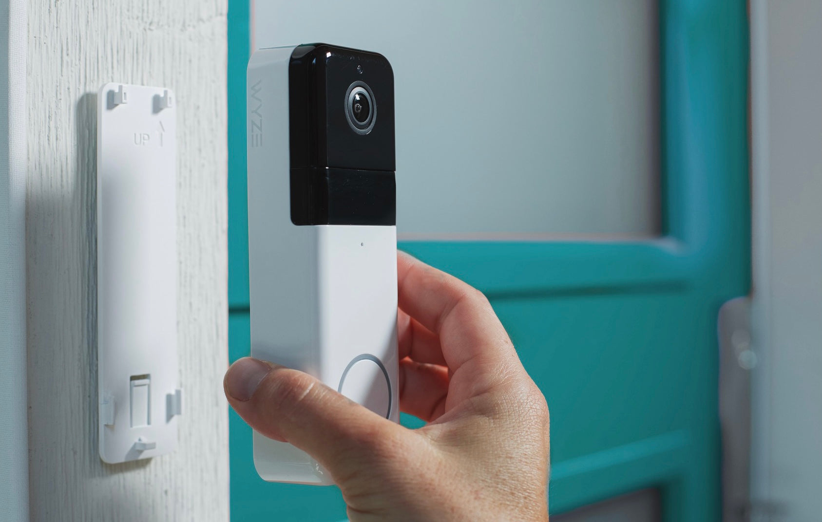 A person holding a white Wyze camera.