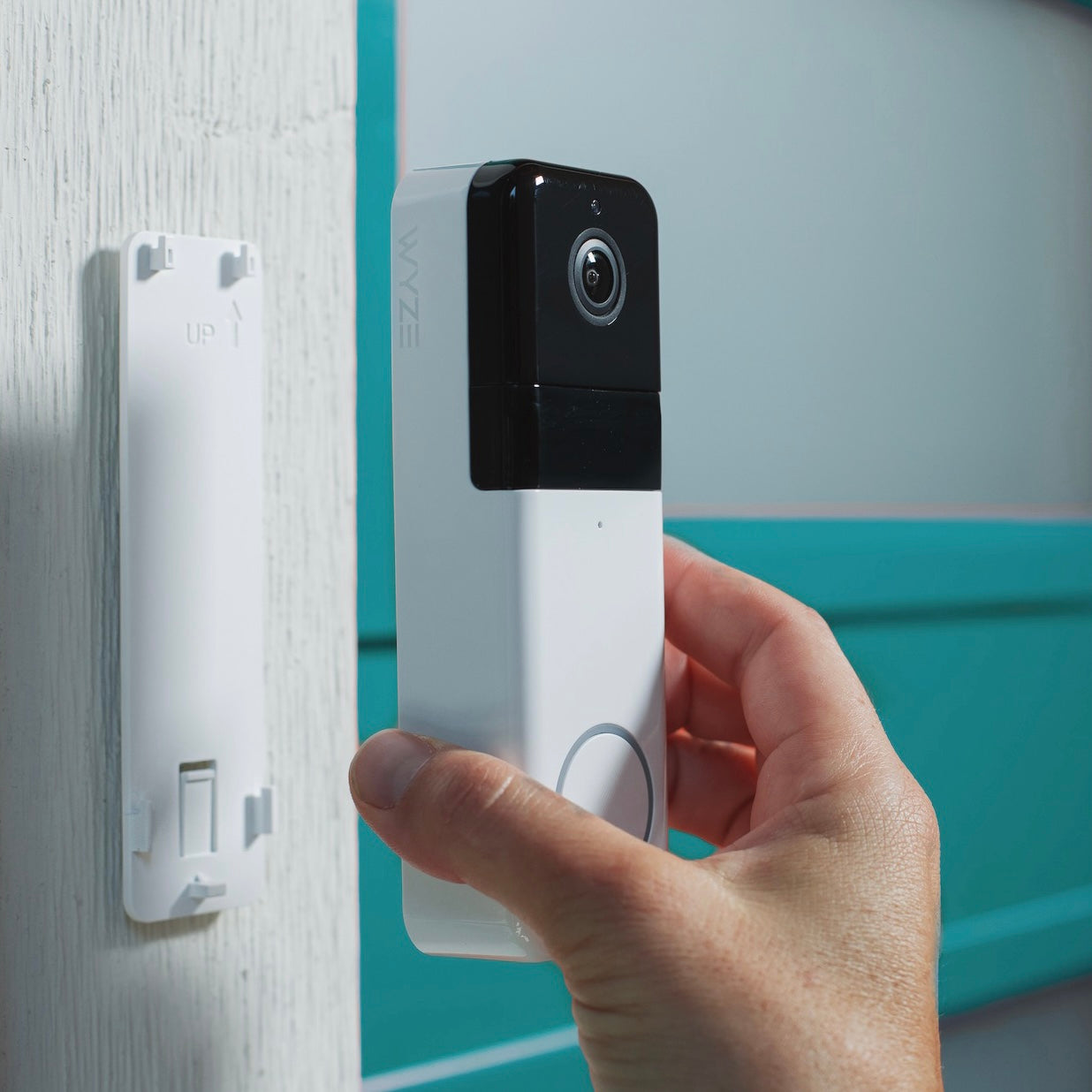 A person holding a white Wyze camera.