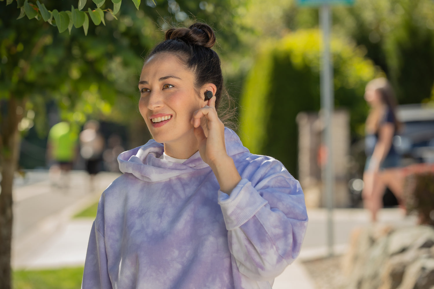 Person touching Wyze buds in their ear with their finger to use touch controls