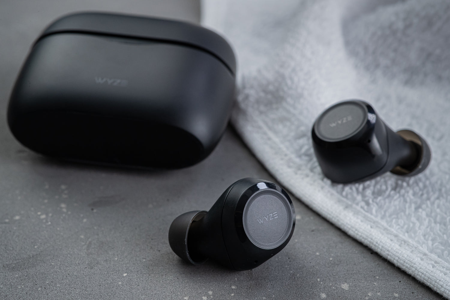 Wyze Buds case and ear buds laying on ground.
