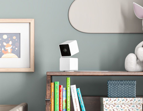 A white camera on a shelf.