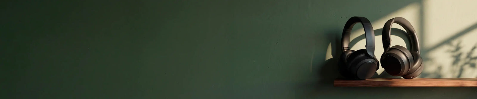 Pair of headphones on a wooden shelf against a green wall