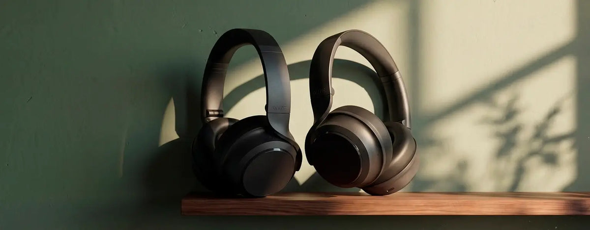 Black headphones on a wooden shelf with a green wall background