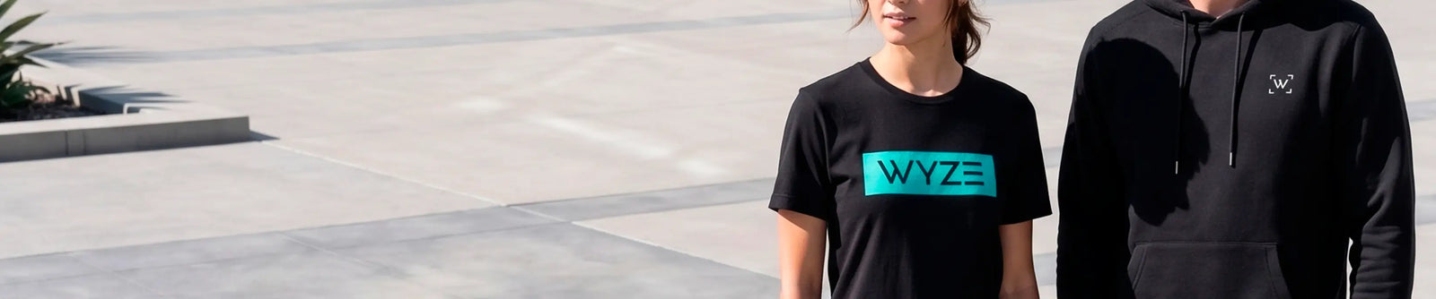 Two people wearing black clothing with visible brand logos outdoors.