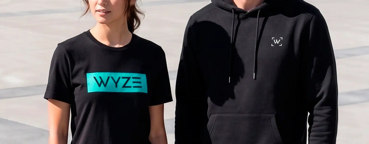 Two people wearing black 'WYZE' t-shirt and hoodie standing outdoors.
