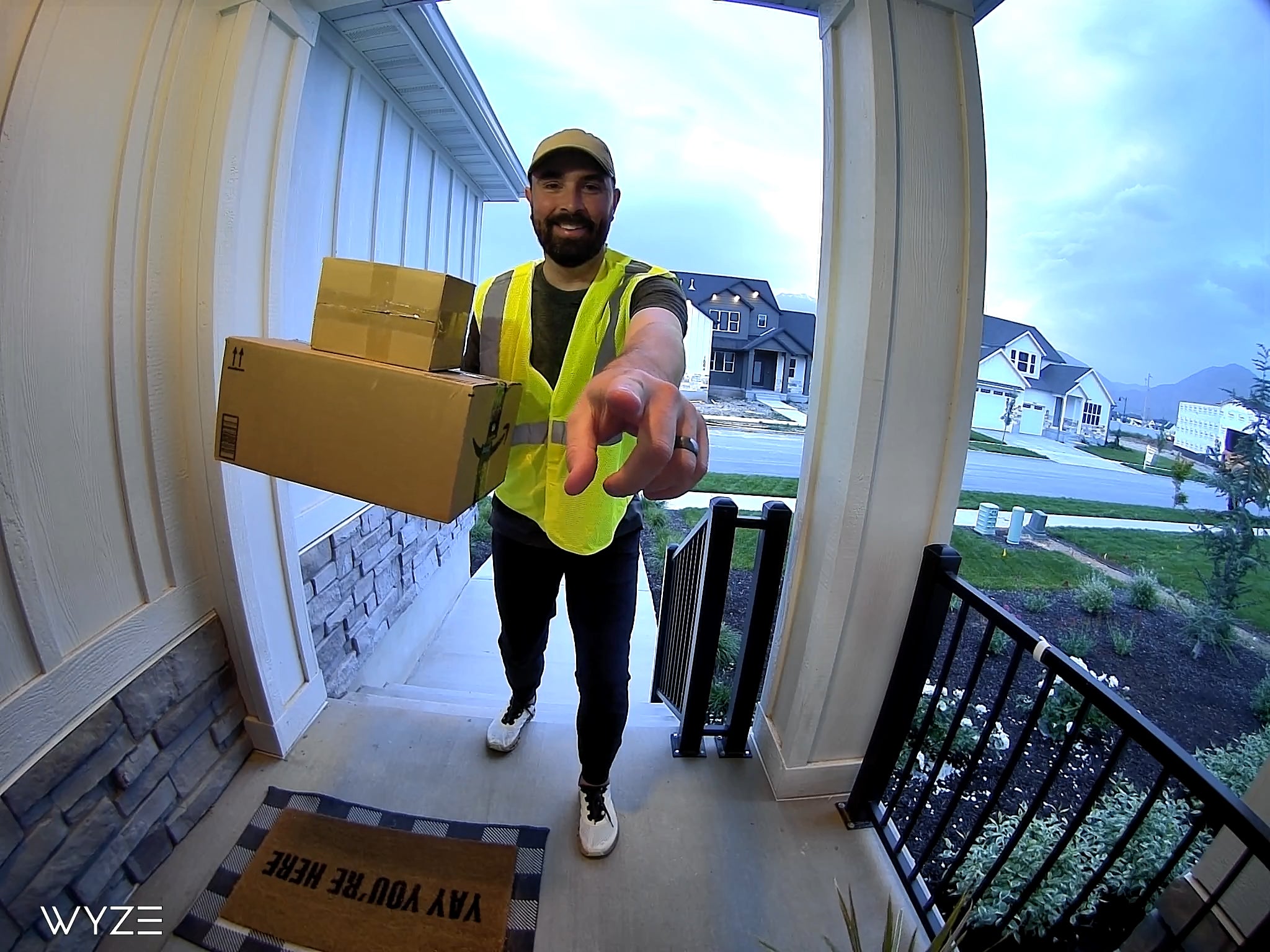 A man in a yellow vest is holding a box.