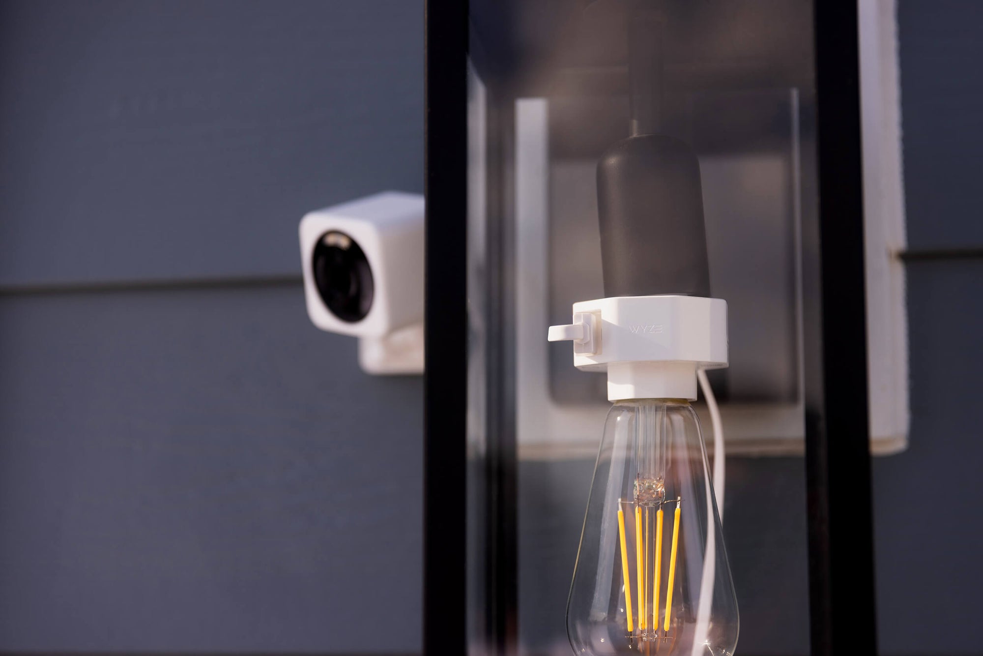 A smart home security camera and light bulb in a fixture on a wall.