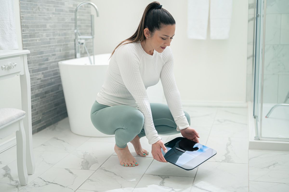 Woman putting black scale on white marble floor