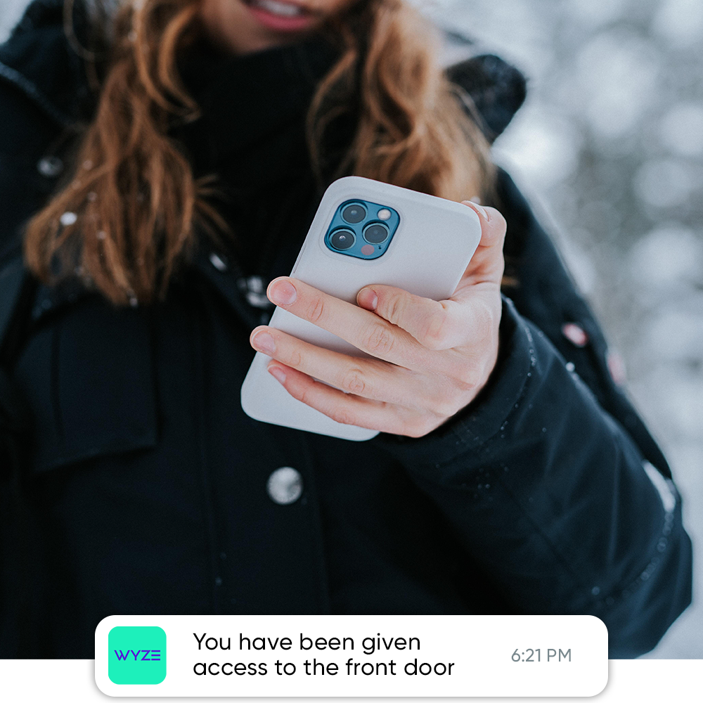 Person holding a phone with an overlay of a phone notification that informs them of a virtual key to the home