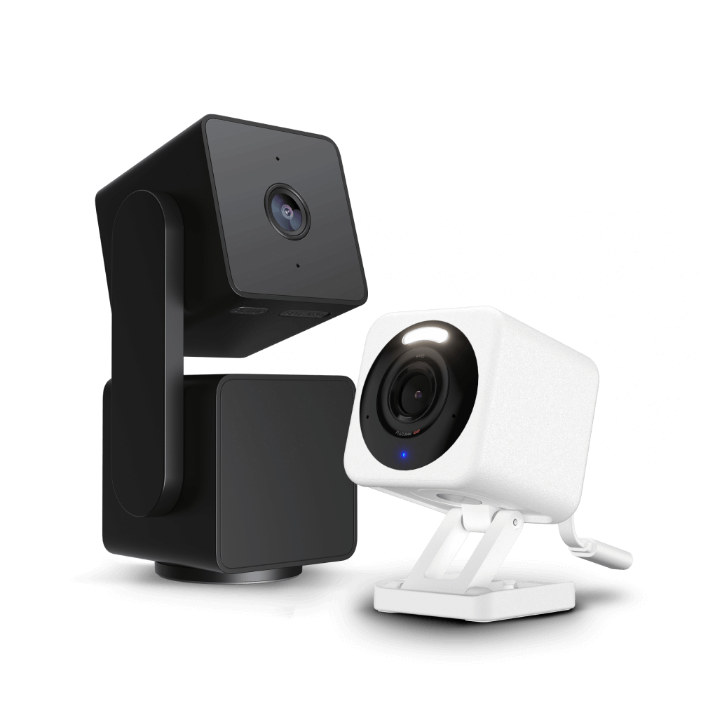Two security cameras, one black and one white, on a black background.