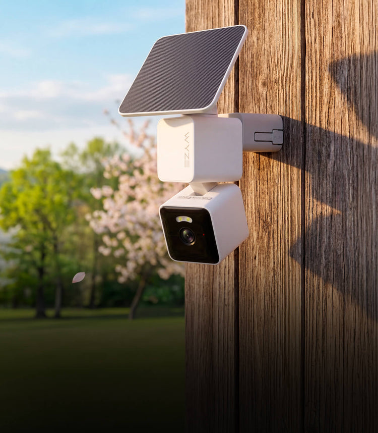 A white camera is mounted on a wooden fence.