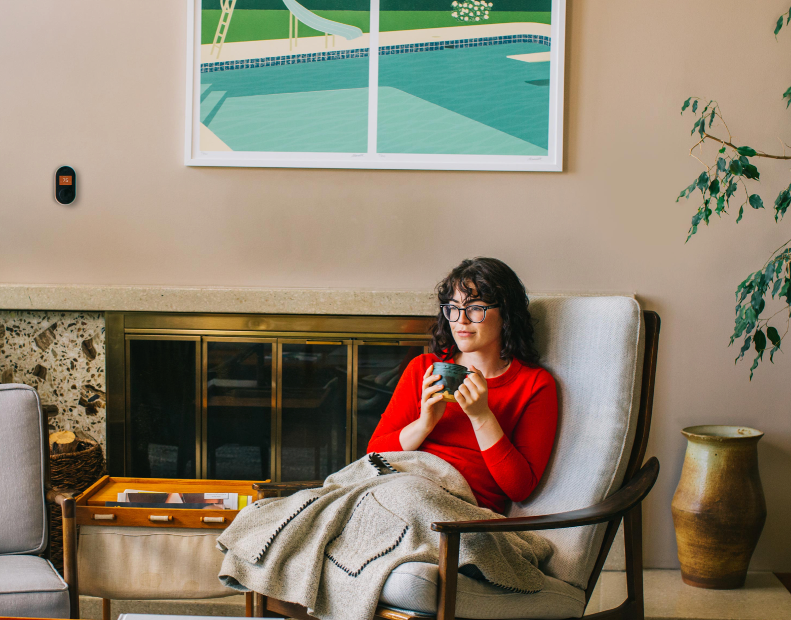 A woman in a red sweater is sitting in a chair, holding a cup.
