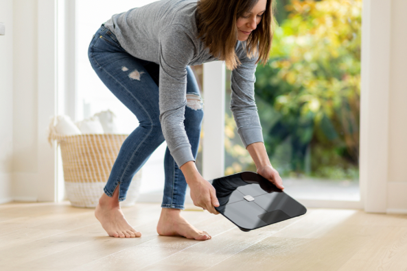 Person bending over to set the Wyze scale on the floor