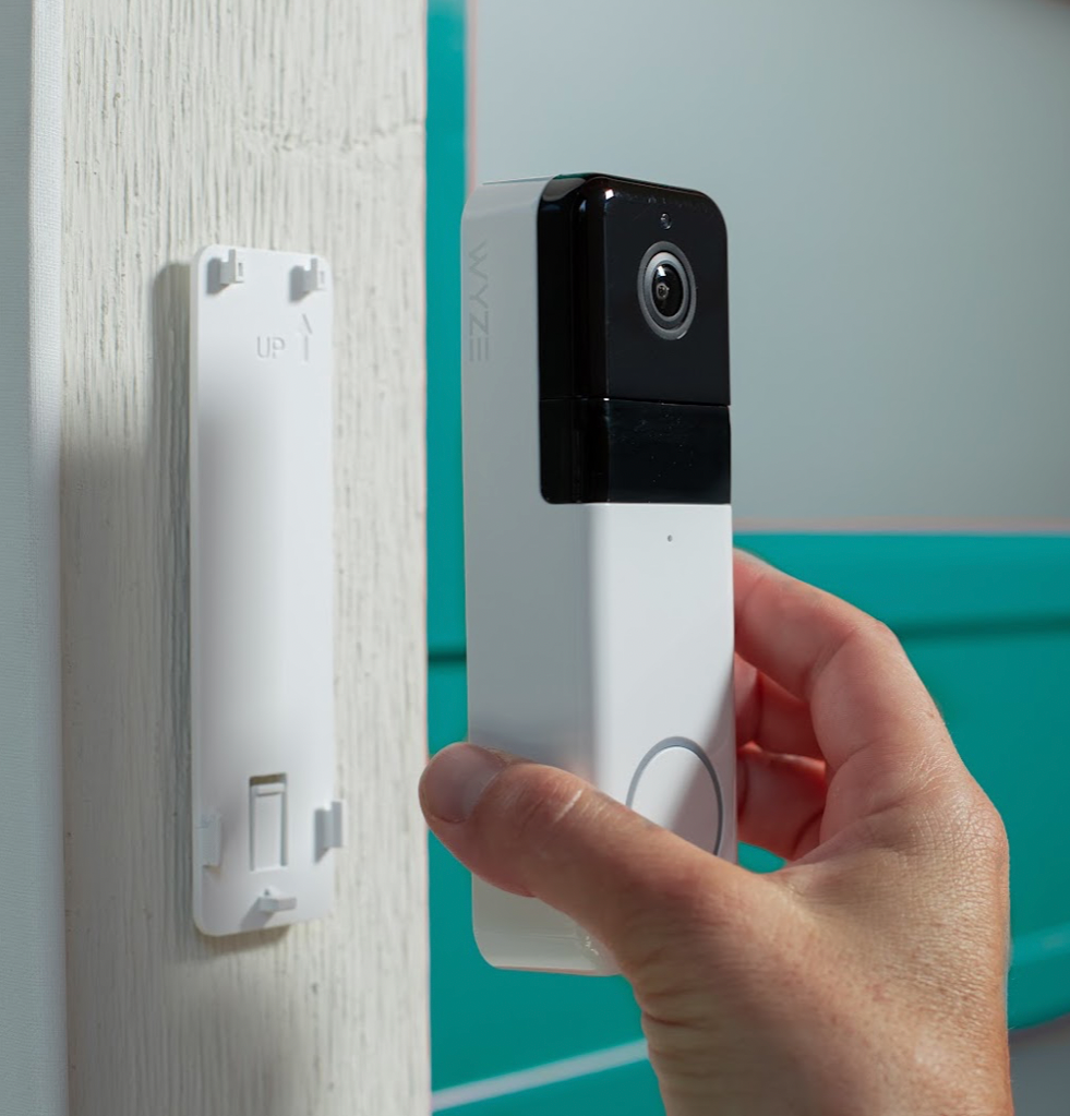 Person installing a Wyze Video Doorbell Pro onto a wall mount plate