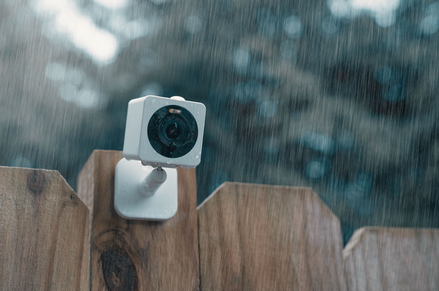 Rain falling onto a outdoor security camera mounted to a fence post