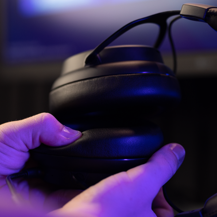 Person holding gaming headset, touching ear pads. 