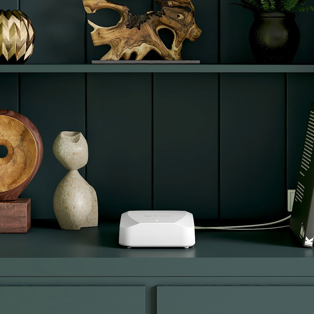 A white Wyze Mesh Router sitting on a shelf.