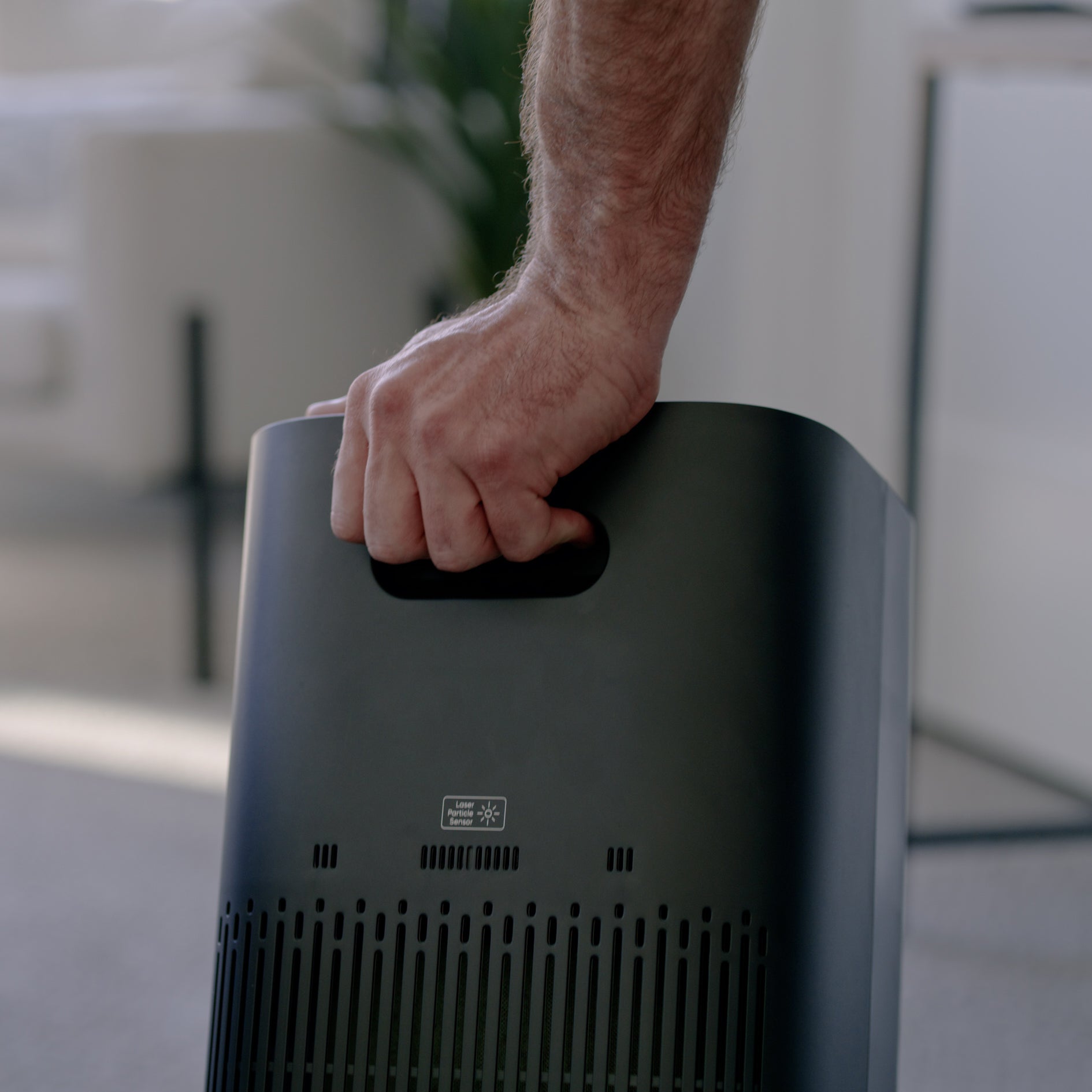 Person holding air purifier by the handle on the back of the purifier 