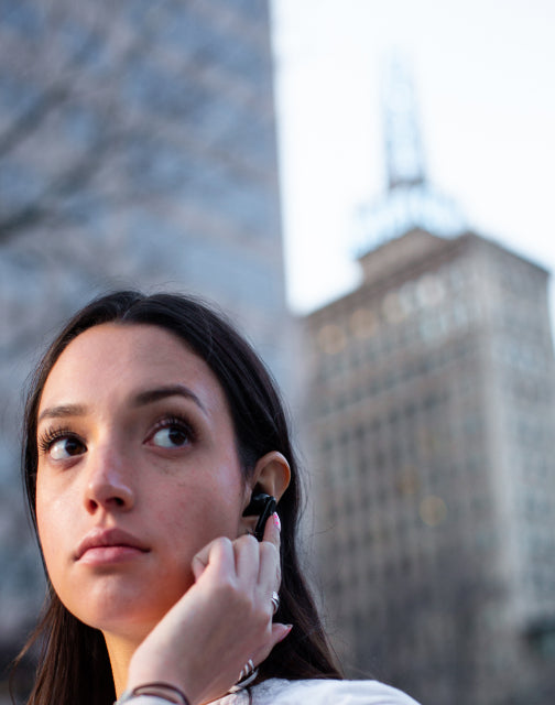 Person wearing wyze buds pro with their finger against the side to engage virtual assistant