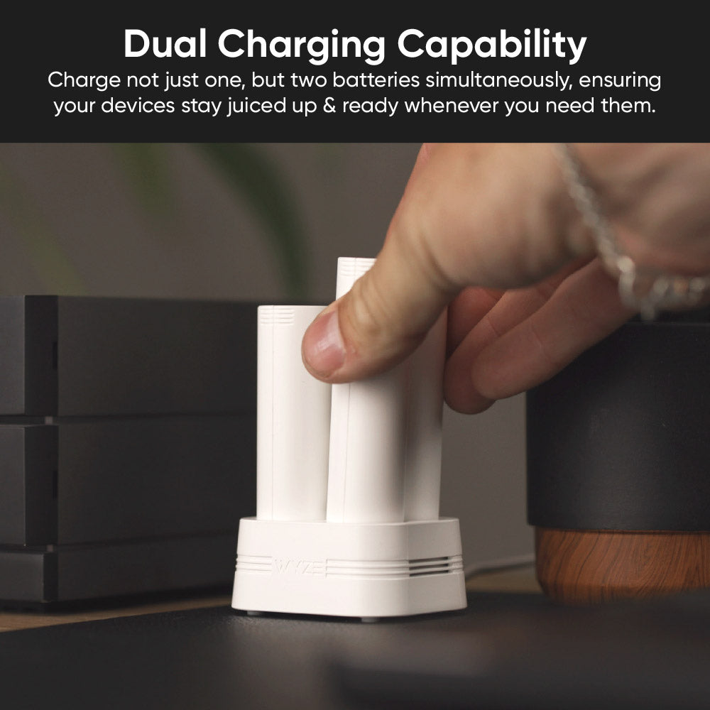 Hand placing a battery pack, next to another battery pack, into charging dock.