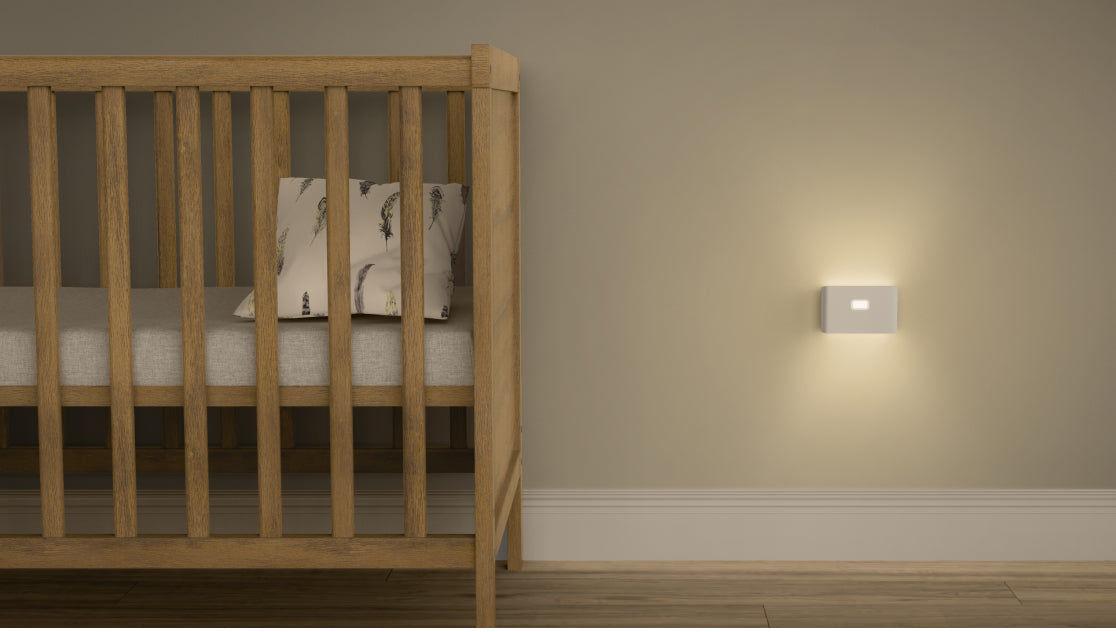 A night light is mounted on the wall next to a crib.