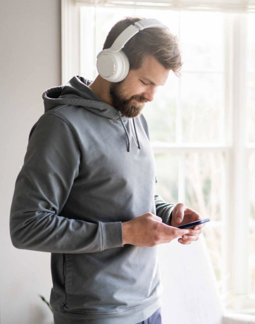 Person wearing white wyze headphones checking their phone