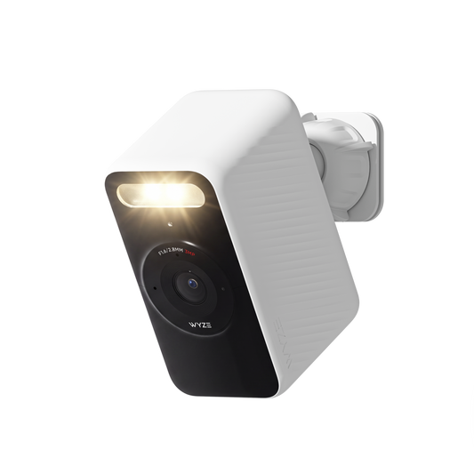 White Wyze Battery Cam shown at an angle with its spotlight illuminated and wall mount attached.