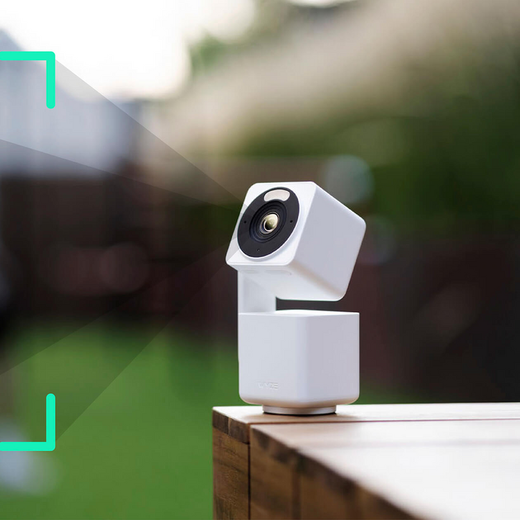 A white Wyze Cam Pan v4 is sitting on a wooden table.