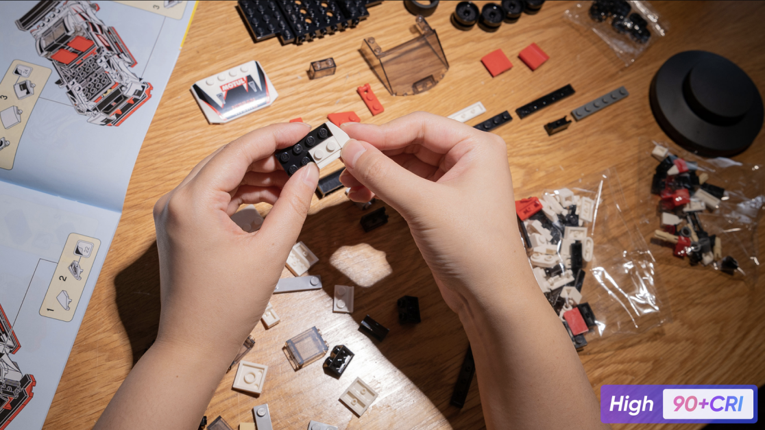 floor lamp shining on person's hands building legos