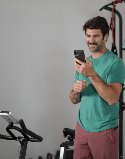 Man looking at his phone with exercise equipment in the background