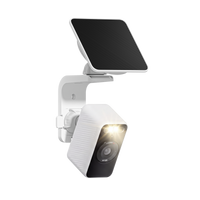 White Wyze Solar Cam with its spotlight illuminated and solar panel mounted above on a wall bracket.