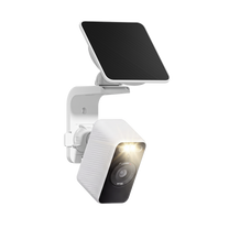 White Wyze Solar Cam with its spotlight illuminated and solar panel mounted above on a wall bracket.