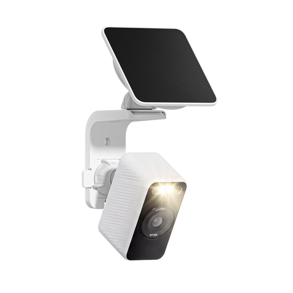 White Wyze Solar Cam with its spotlight illuminated and solar panel mounted above on a wall bracket.
