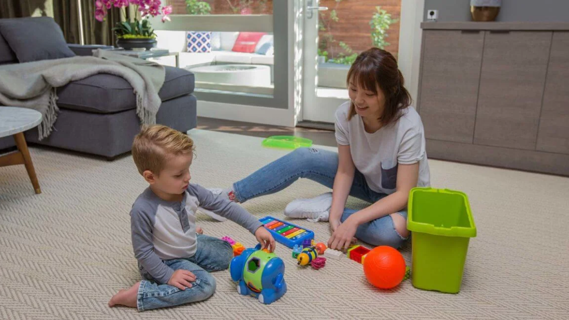 A woman and a child playing with toys on the floor.