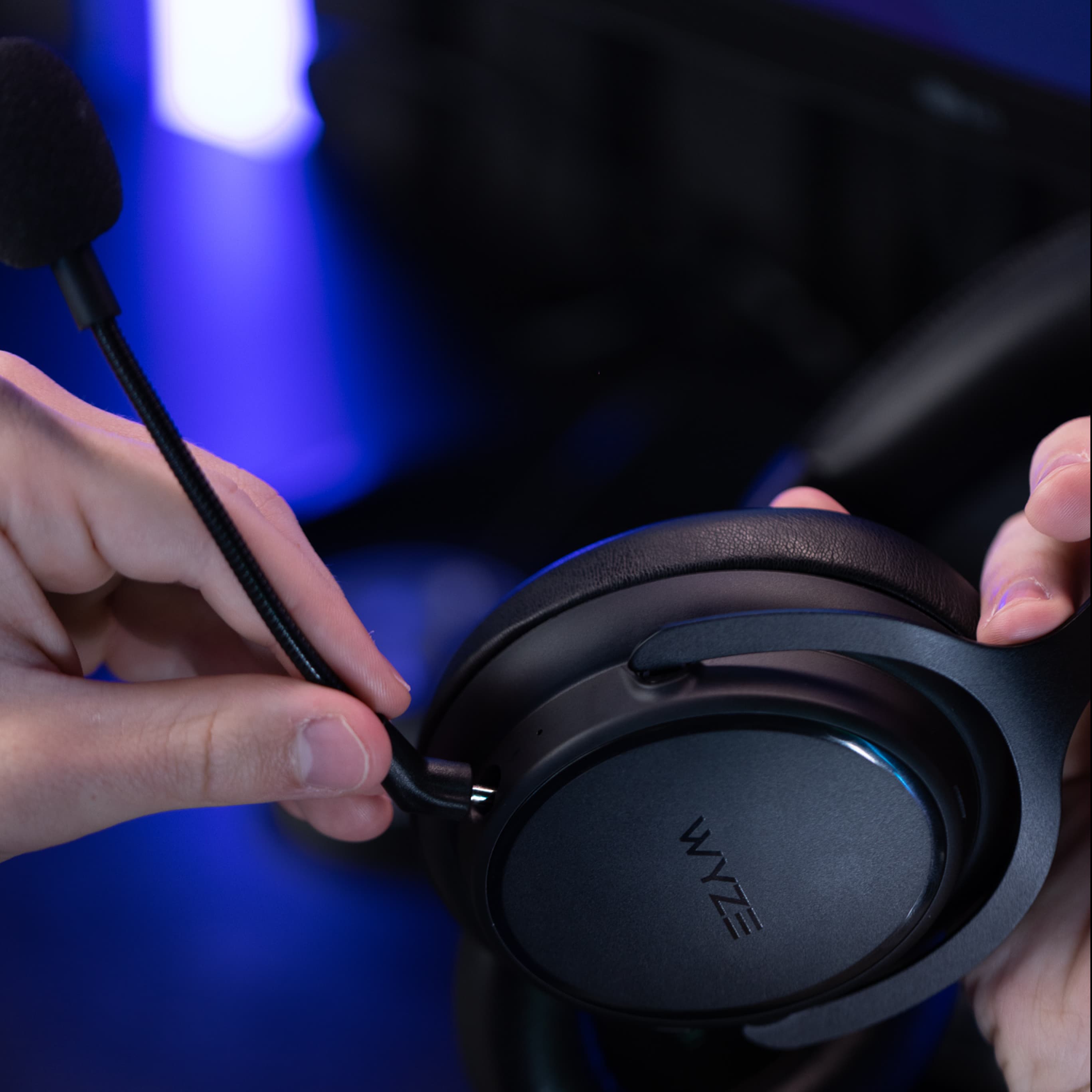 Person plugging detachable boom mic into gaming headset.
