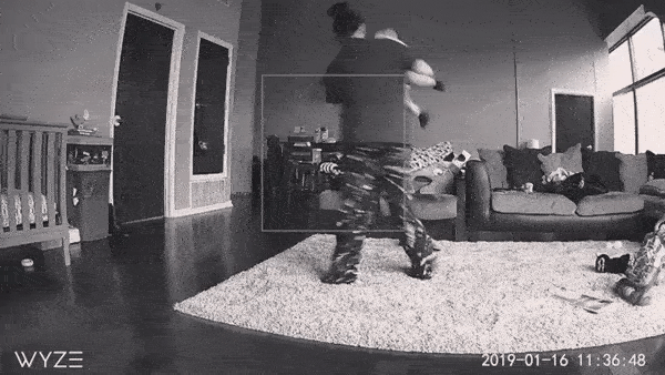 A man is holding a baby while standing in a living room. 1