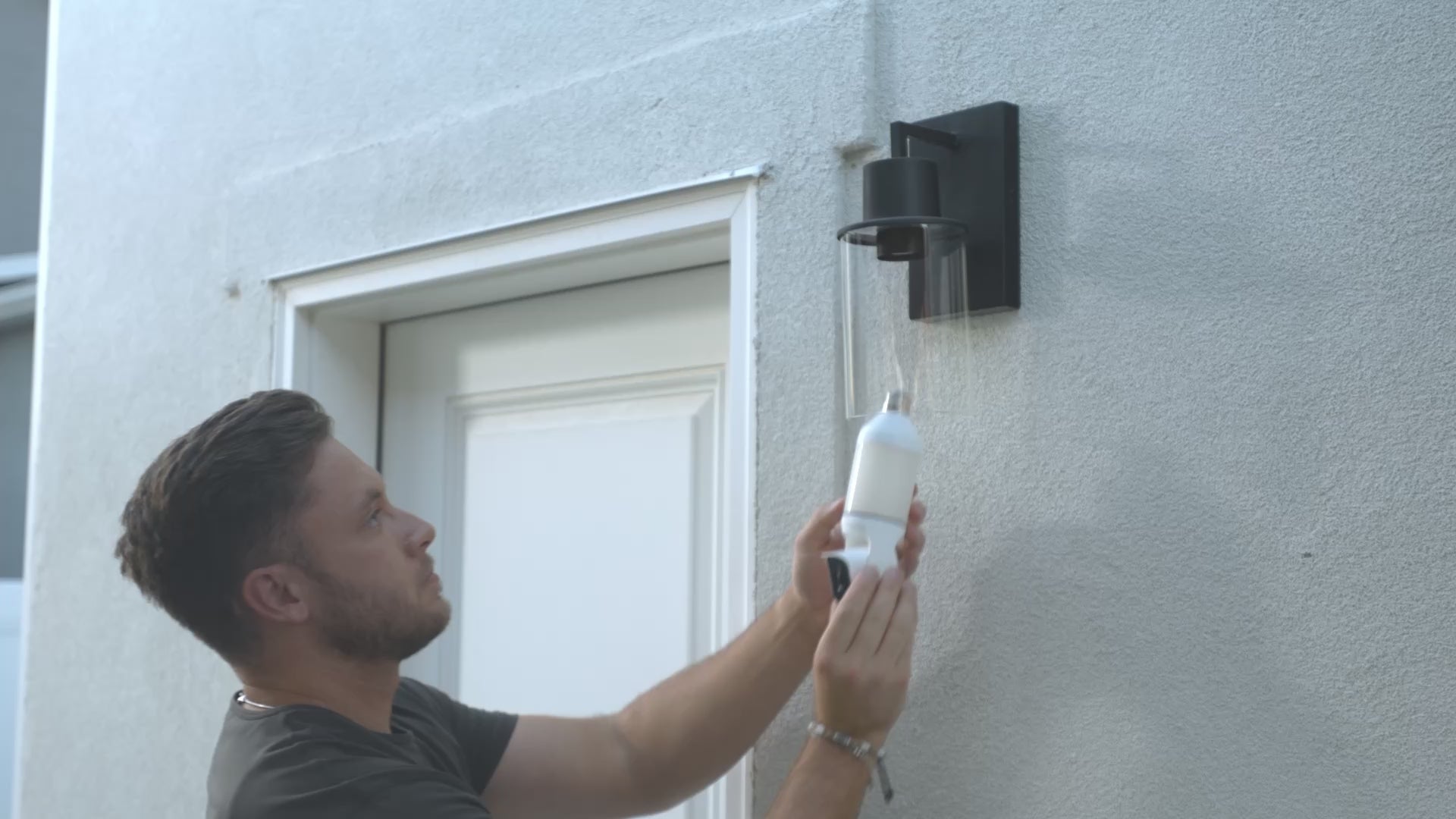 Cargar video: Hombre instalando una cámara de seguridad con bombilla en una luminaria.