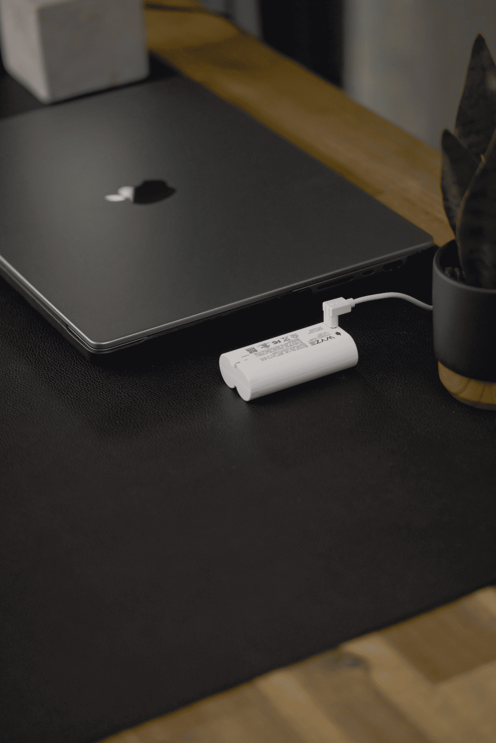 A white battery attached to a black laptop.