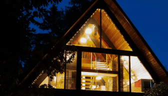 Exterior view of home during late evening with all of its lights on.