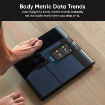 A person is standing on a Wyze Scale Ultra BodyScan, which measures 13 body composition metrics.