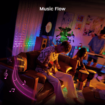 A man playing a guitar in a living room with a woman sitting on a couch.
