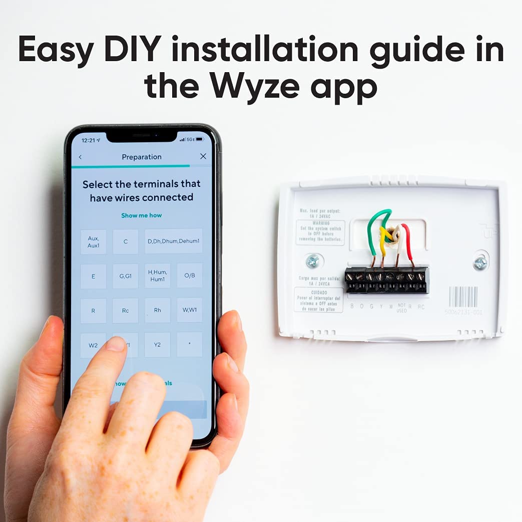 Hands holding up a smartphone with Wyze app and installation instructions open. To the right is a wall mount of a traditional theromostat unit that has been removed. Black text overlay that says "Easy DIY installation guide in the Wyze app." 