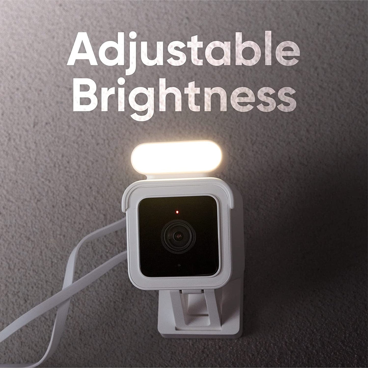 Wyze Cam v3 with a spotlight attached and is installed on a wall. Text overlay that says "Adjustable Brightness."