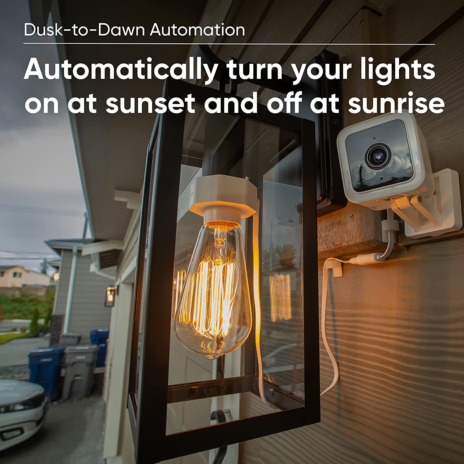 Wyze Lamp Socket with an edison bulb installed and is turned on. Wyze Cam v3 with wiring lining the wall and attached to the Lamp Socket. Text overlay that says "Dusk to Dawn automation."