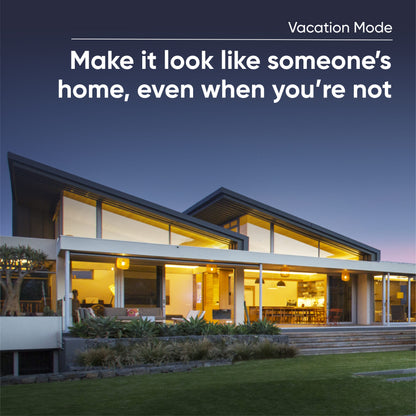 Front view of a large home with the lights on in various rooms. White text overlay that says "Vacation Mode."