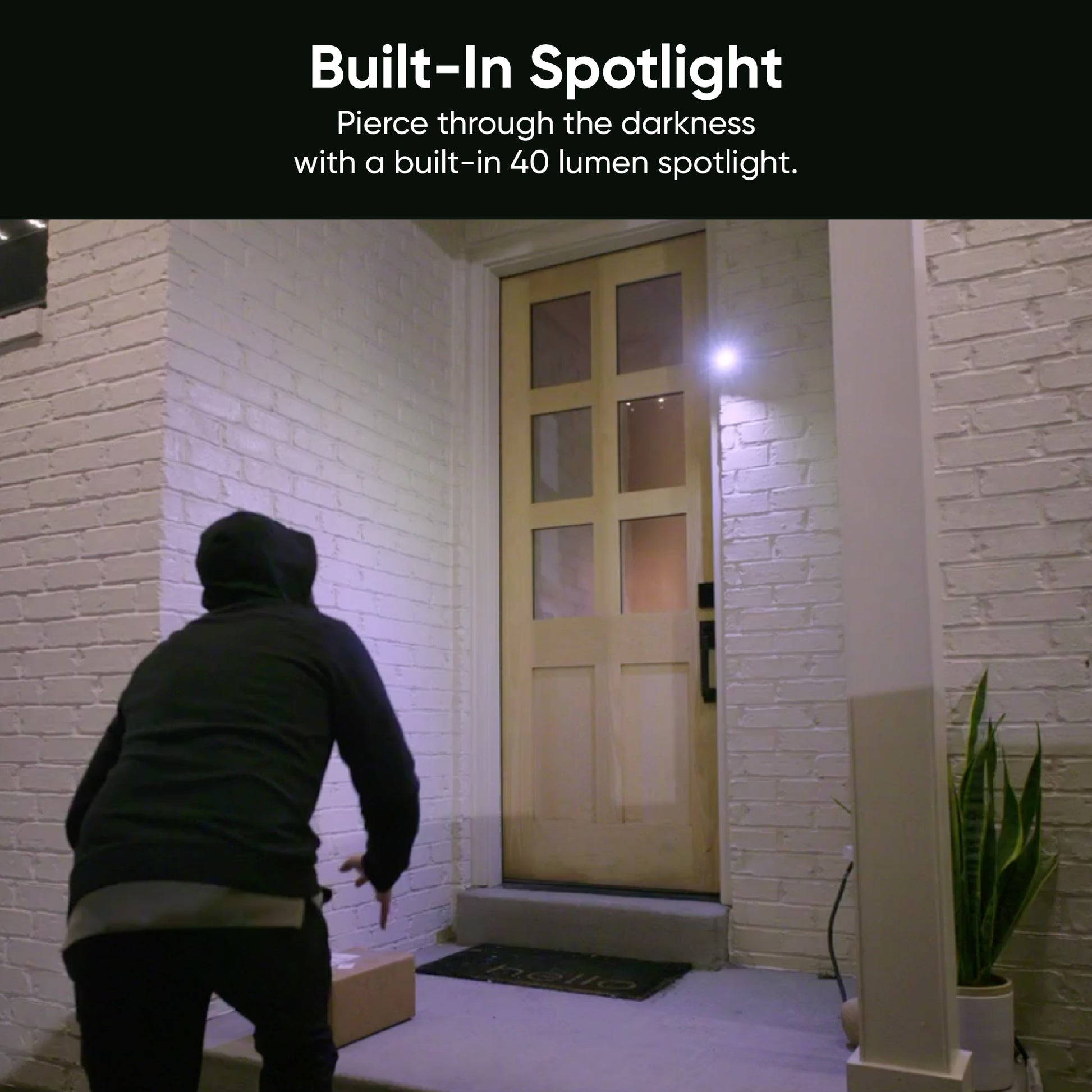 Built-in spotlight shining on hooded figure approaching a package on the front porch. Text overlay "Built-In Spotlight."